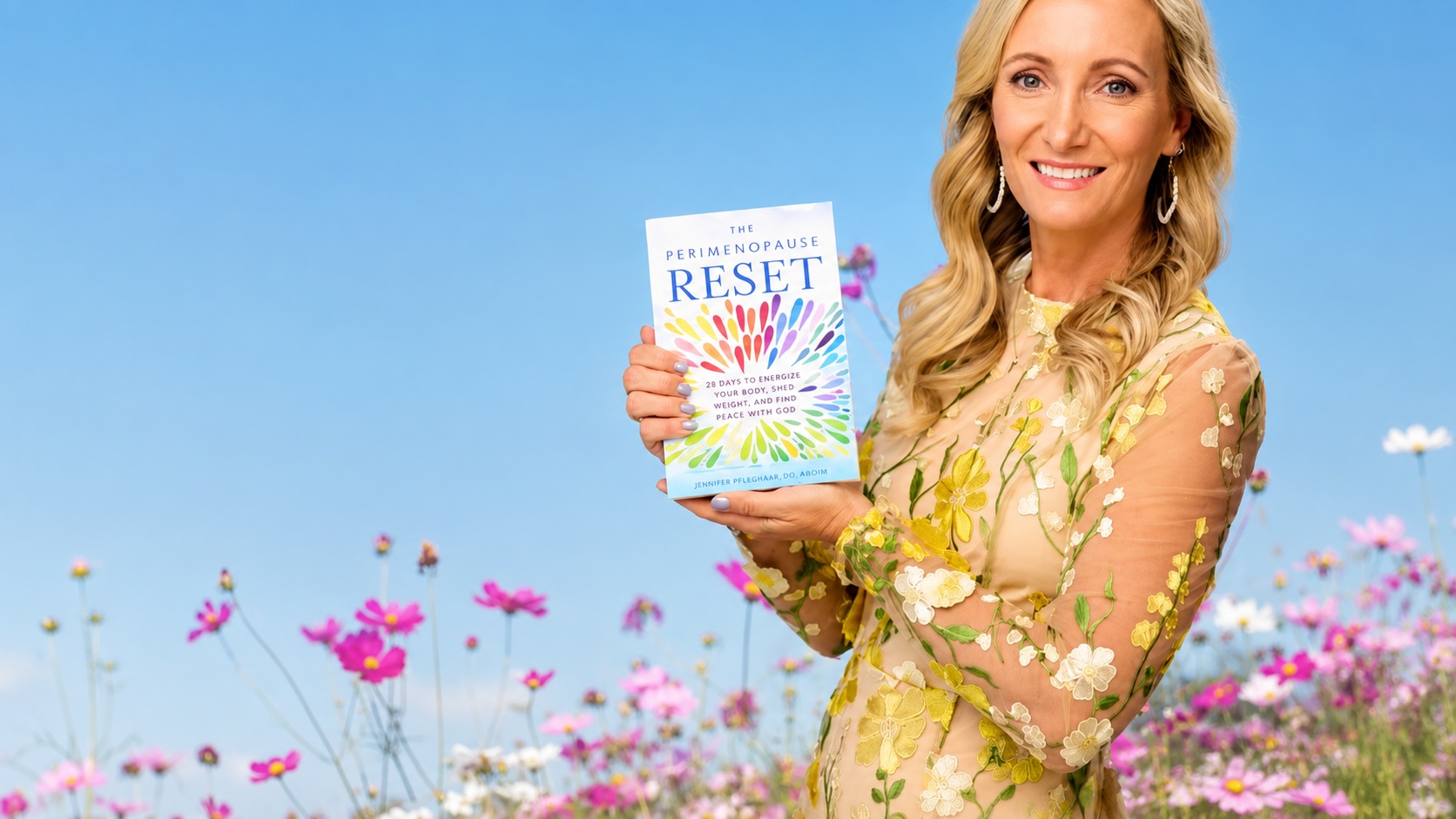 Dr. Jen Pfleghaar holding The Perimenopause Reset book in a wildflower field